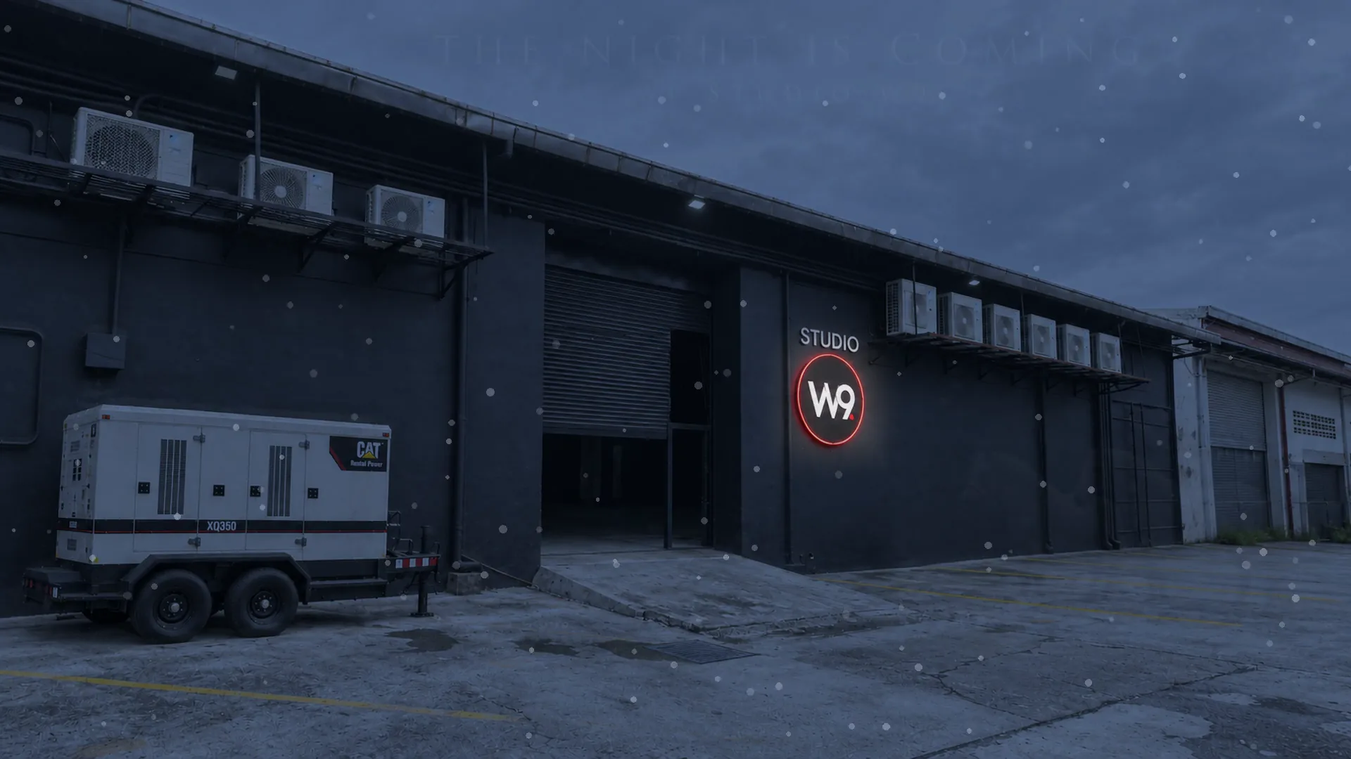 Studio W9 facade at night with the illuminated W9 sign as the first snow begins to fall — a frame from the Maximum Aura promotional film